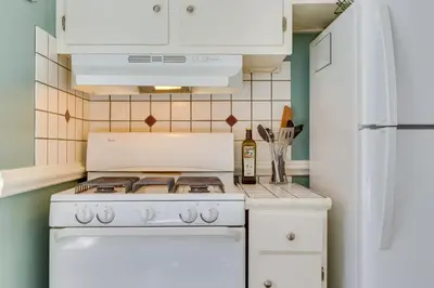 a kitchen with a white stove top oven next to a refrigerator at 2 Mi to Washington Park Convenient Denver Home! in Denver
