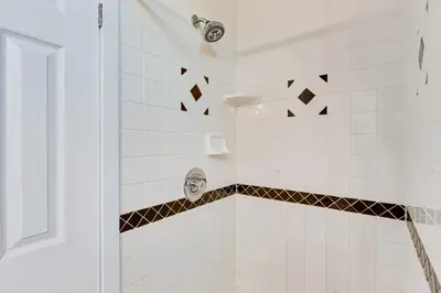 a white tiled shower with a mask on the wall at 2 Mi to Washington Park Convenient Denver Home! in Denver