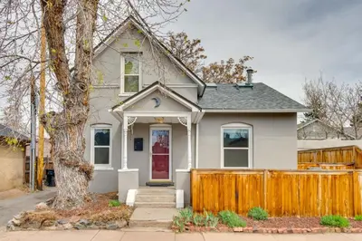a white house with a wooden fence at 2 Mi to Washington Park Convenient Denver Home! in Denver