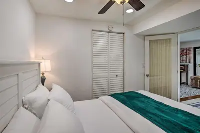 a bedroom with a white bed and a ceiling fan at 4 Mi to Coors Field Charming Apartment with Patio in Denver