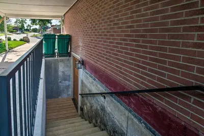 a brick wall with stairs and two green trash cans at 4 Mi to Coors Field Charming Apartment with Patio in Denver