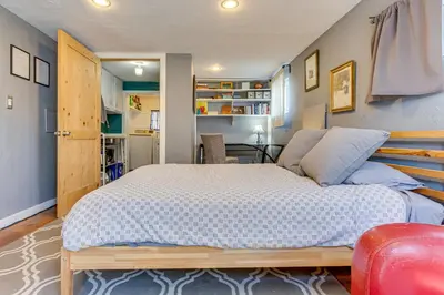 a bedroom with a large bed and a red chair at Platt Park Studio with Patio Walkable Location! in Denver