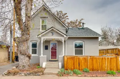 a white house with a wooden fence at Platt Park Studio with Patio Walkable Location! in Denver