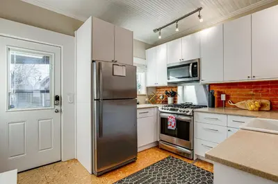 a kitchen with white cabinets and a stainless steel refrigerator at Stay and Play in South Denver! 7 Mi to LoDo in Denver