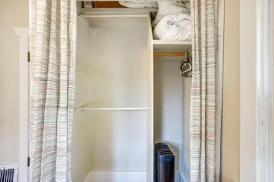 a walk in closet with white shelves and curtains at Stay and Play in South Denver! 7 Mi to LoDo in Denver