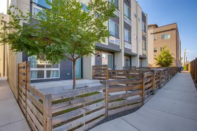 a wooden fence with a tree in front of a building at Rooftop Deck and Hot Tub Walkable Denver Townhome in Denver