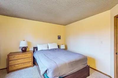 a bedroom with a bed and a dresser with a lamp at Lookout Lounge in Fraser