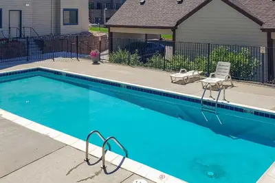 a large blue swimming pool in a yard with a house at Condo with Patio and Pool Access in Greenwood Village! in Greenwood Village
