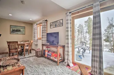 a living room with a table and a television and a window at Cozy Mountain Getaway with Ski Shuttle Access! in Fraser