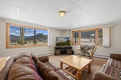 a living room with a couch and a table and a tv at Lily Mountain Lodge - Amazing Mountains Views, Private Hot Tub, Great Location in Estes Park