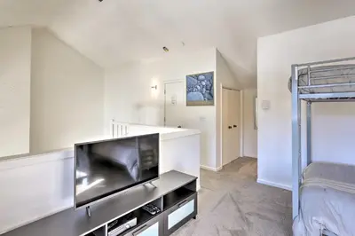 a living room with a flat screen tv and a bed at Walkable Winter Park Condo about 4 Mi to Slopes! in Winter Park