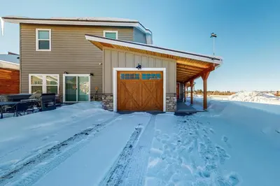 a house with a wooden garage in the snow at Quail Nest on Quail Drive in Fraser