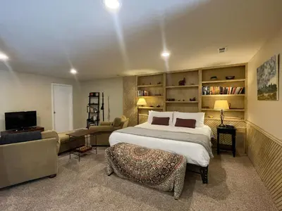 a bedroom with a large bed and a living room at Couples Retreat with Hot Tub, Sauna and Steam Room in Fort Collins