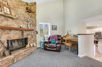 a living room with a stone fireplace and a chair at Misty Meadow in Fraser
