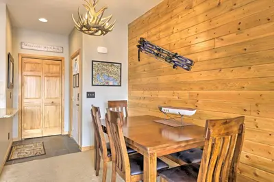 a dining room with a wooden wall with a table and chairs at Mountainside Grand Lake Condo with Patio! in Grand Lake