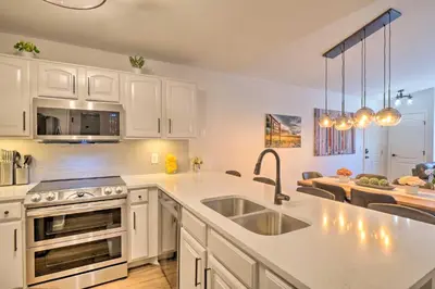 a kitchen with white cabinets and a sink and a table at Balcony and Hot Tub Access Modern Breck Escape! in Breckenridge