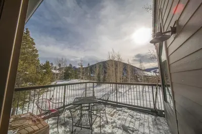 a balcony with a table and chairs in the snow at Quicksilver 1618 by SummitCove Lodging in Keystone