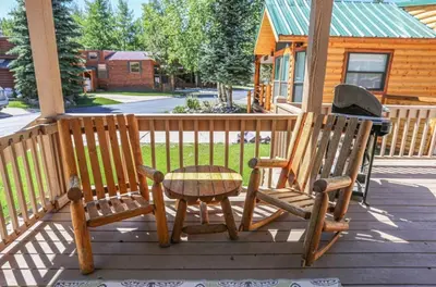 two wooden chairs and a table on a porch at Sun & Snow Chalet Breckenridge, a dog lovers dream! in Breckenridge