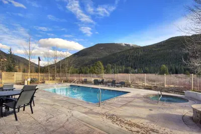 a swimming pool with a table and chairs and mountains at Red Hawk Lodge Condo in Keystone