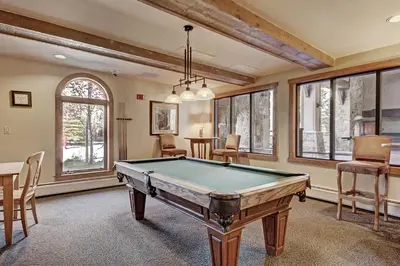a pool table in a room with windows at Red Hawk Lodge Condo in Keystone