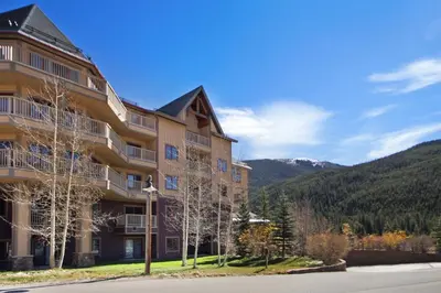 a large apartment building with mountains in the background at Red Hawk Lodge Condo in Keystone