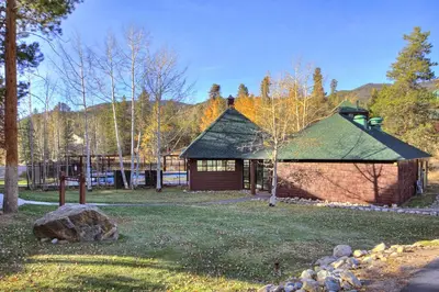 a log cabin with a green roof in a park at Soda Springs Condominiums in Keystone