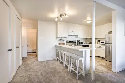 a kitchen with white cabinets and a counter with stools at Steps to Dillon Reservoir Mtn-View Condo in Dillon