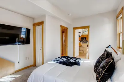 a bedroom with a white bed and a flat screen tv at Brilliant Posh Home - Backs to Poudre River Trail! in Fort Collins