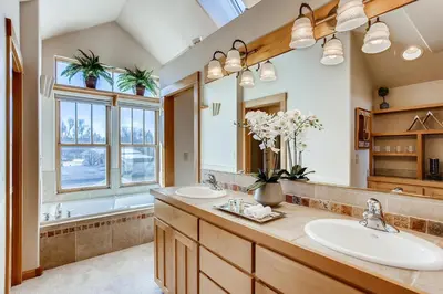 a bathroom with two sinks and a large mirror at Brilliant Posh Home - Backs to Poudre River Trail! in Fort Collins