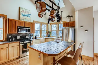 a kitchen with wooden cabinets and a counter top at Brilliant Posh Home - Backs to Poudre River Trail! in Fort Collins