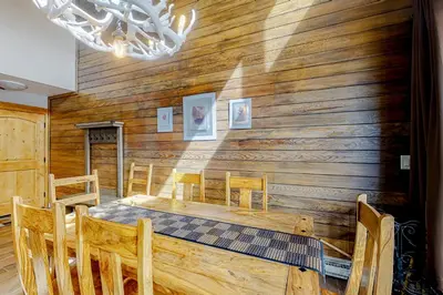 a dining room with a wooden wall with a table and chairs at Montezuma Magic in Keystone