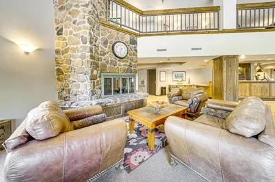 a living room with couches and a stone fireplace at Chic Winter Park Studio with Community Hot Tub in Winter Park