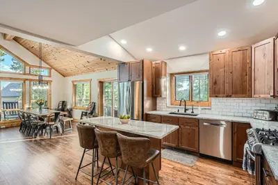 a kitchen with wooden cabinets and a table with bar stools at Moose Ridge Cabin cabin in Grand Lake