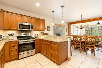 a kitchen with wooden cabinets and a dining room with a table at 8201 Mill Creek - Private Hot Tub! condo in Dillon