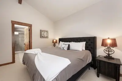 a bedroom with a large bed with white sheets at Bear Trail townhouse in Winter Park