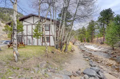 a house in the woods next to a river at Fall River Casita in Estes Park