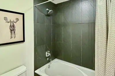 a bathroom with a shower and a tub with a deer on the wall at Pine Peak in Fraser