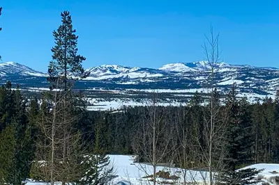 a view of a snowy mountain range with trees and a lake at Pine Peak in Fraser