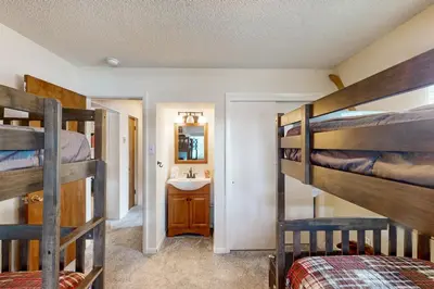 a bedroom with two bunk beds and a sink at Hi Country Haus Hideaway in Winter Park