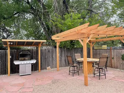 a wooden gazebo with a table and chairs and a stove at Charming Vintage Cottage with Hot Tub & Free Bikes! in Fort Collins