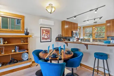 a kitchen with a wooden table and blue chairs at Sleek Condo - Near Park, Poudre River and Old Town in Fort Collins