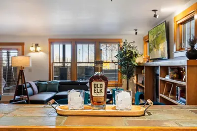 a bottle of whiskey on a tray on a table at Sleek Condo - Near Park, Poudre River and Old Town in Fort Collins