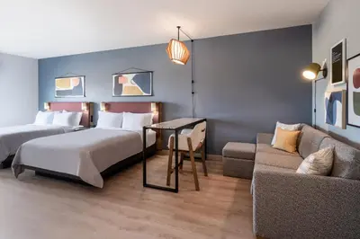 a hotel room with two beds and a couch at Atwell Suites Denver Airport - Tower Road by IHG in Denver