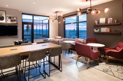 a dining room with tables and chairs and windows at Atwell Suites Denver Airport - Tower Road by IHG in Denver
