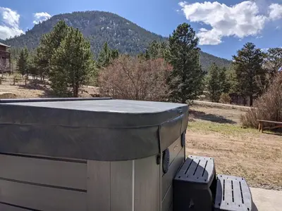 a hot tub sitting next to a bench with a mountain at Rocky Mountain Retreat 1B by Rocky Mountain Resorts in Estes Park