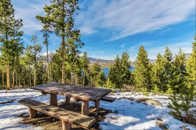 a picnic table in the snow with a view of a lake at 309 Snowdance Manor condo in Keystone