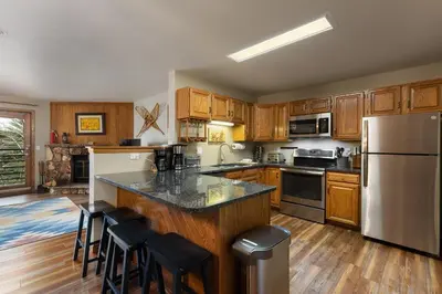 a kitchen with wooden cabinets and a stainless steel refrigerator at 309 Snowdance Manor condo in Keystone