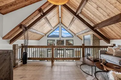 a living room with wooden ceilings and a large window at Brand NEW Located on Lake Estes Private Jacuzzi Two Patios Indoor and Outdoor Fireplace in Estes Park