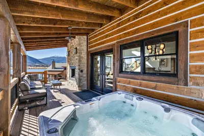 a hot tub on the deck of a house at Brand NEW Located on Lake Estes Private Jacuzzi Two Patios Indoor and Outdoor Fireplace in Estes Park