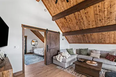 a living room with a couch and wooden ceilings at Brand NEW Located on Lake Estes Private Jacuzzi Two Patios Indoor and Outdoor Fireplace in Estes Park